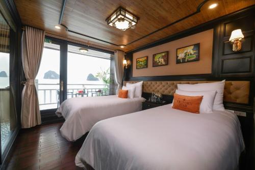 two beds in a room with a window at Victory Star Cruise in Ha Long