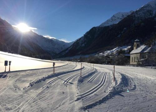 a snowy road with the sun shining on a mountain at Ferienhaus Leite Häusl in Sankt Jodok am Brenner