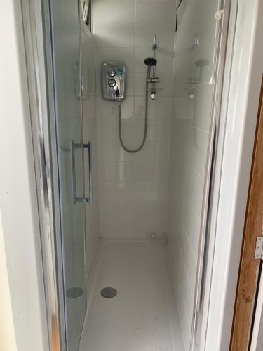 a shower stall with a glass door with a shower at Cosy Beach Chalet in Scratby