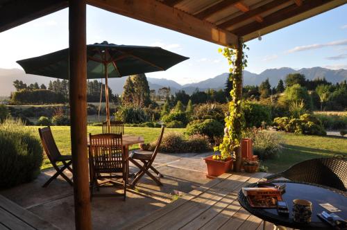 a patio with a table and an umbrella at Blue Thistle Cottages in Te Anau