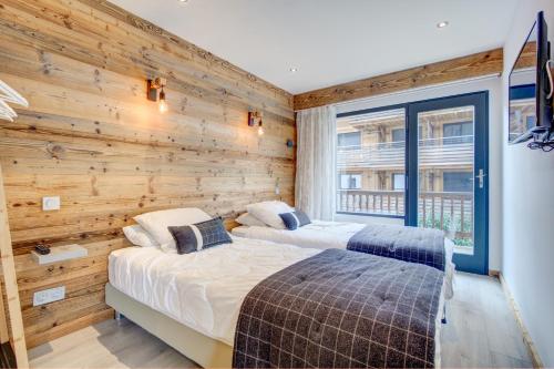 two beds in a room with a wooden wall at Edelweiss Cosy in Morzine