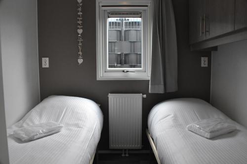 two beds in a small room with a window at Chalet ‘Het Giethoornsche Meer’ (16) in Giethoorn