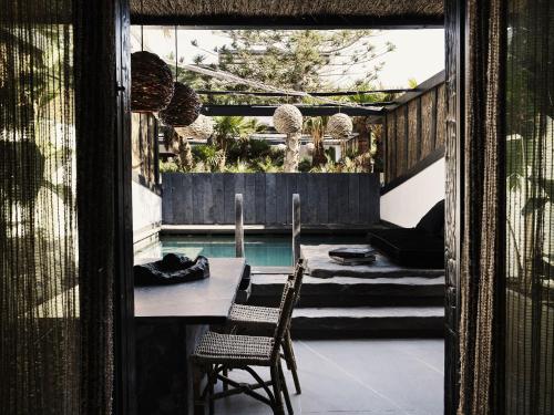 a patio with a table and chairs next to a pool at Myconian O, a Member of Design Hotels in Ornos
