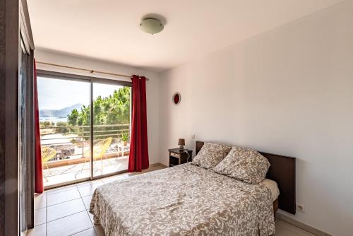 um quarto com uma cama e uma grande janela em Calvaro - Appartement classé 5 étoiles - vue mer em Calvi