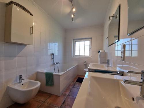 a bathroom with two sinks and a bath tub and a tubermott at Ferienhaus Im Hasengrund in Dornumersiel