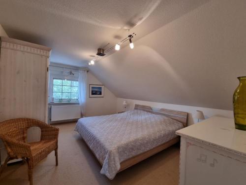 a bedroom with a bed and a chair and a window at Ferienhaus Im Hasengrund in Dornumersiel