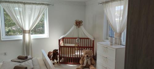 a baby room with a crib with a teddy bear in it at Chata u kolára in Malatiná