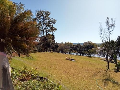 een grasveld met bomen en een waterlichaam bij Duiker's Den at Hulala in White River