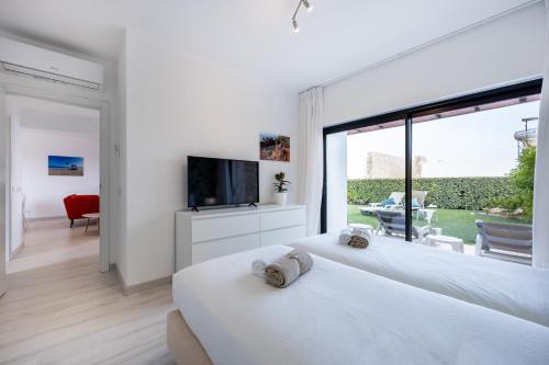 two white beds in a room with a large window at Villa Sagres Surf in Sagres