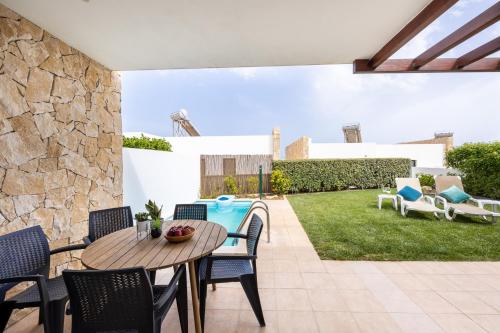 a patio with a table and chairs and a yard at Villa Sagres Surf in Sagres