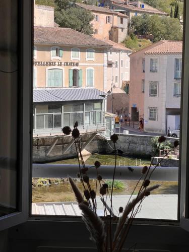 a view of a building from a window with a plant at Studio "Le Fontaine de Vaucluse" in Fontaine-de-Vaucluse