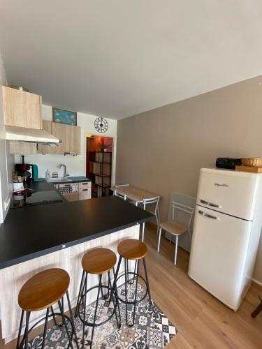 une cuisine avec un comptoir noir et des tabourets dans l'établissement U064 - La marmotte enchantée - Gréolières les Neiges, à Gréolières