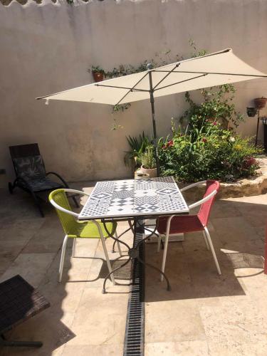 a table and chairs with an umbrella on a patio at Les Remparts de Lauris Coeur Médiéval et Patio in Lauris