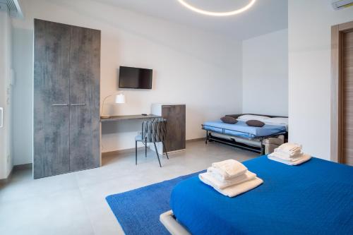 a bedroom with a blue bed and a kitchen at Il Crepuscolo Marzamemi in Marzamemi