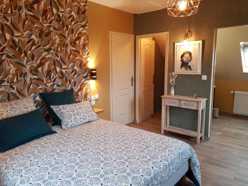 a bedroom with a bed and a table and a wall at Chambres d hôtes de la Mauguinière in Neuillé-le-Lierre