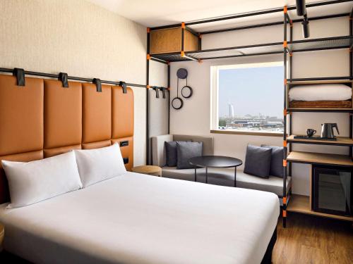 a hotel room with a bed and a window at Ibis Al Barsha in Dubai