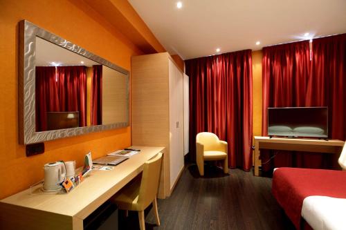 a hotel room with a desk and red curtains at Best Western Hotel Piemontese in Bergamo