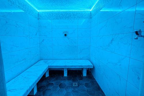a blue room with a bench in the shower at Holiday Club Apartman Hotel in Hévíz