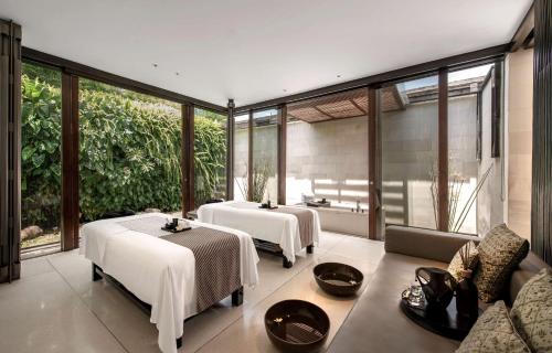 two beds in a room with windows at Alila Villas Uluwatu in Uluwatu