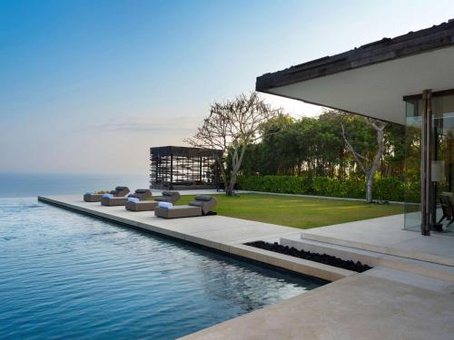 a row of lounge chairs sitting on the edge of a swimming pool at Alila Villas Uluwatu in Uluwatu