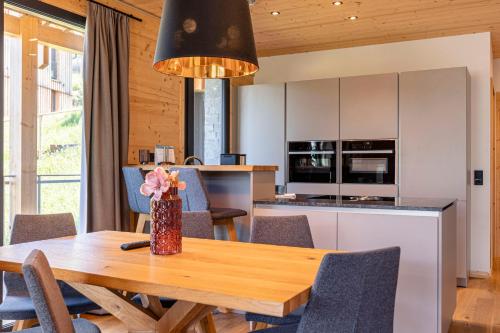 a kitchen and dining room with a wooden table and chairs at Bergresort Hauser Kaibling by ALPS RESORTS in Haus im Ennstal