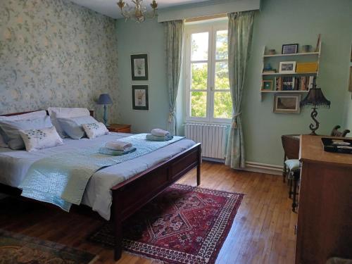 a bedroom with a bed and a desk and a window at La Grange Terrou in Saint-Germain-de-Confolens