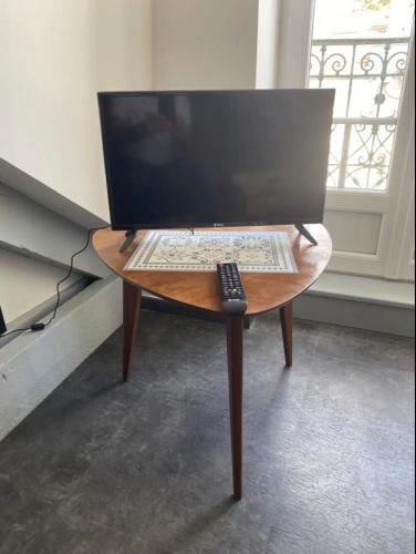 a wooden table with a computer monitor and a remote control at Le Grenier Saint-Pierre in Verdun