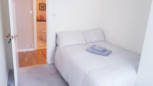 a white bed with a blue towel on top of it at Lovely 2 bedroom flat in the heart of water Wimbledon in London