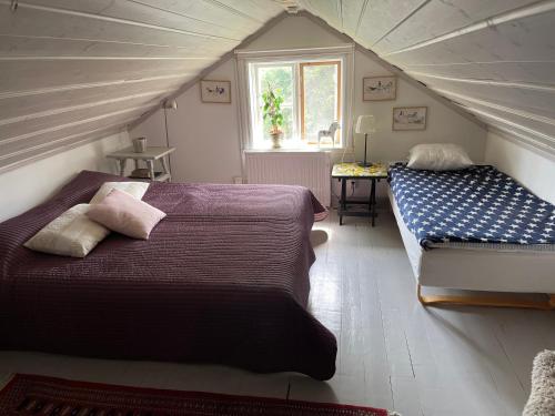 a attic bedroom with two beds and a window at Cozy lodge at horse farm with lake and sauna in Hölö