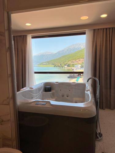 a bath tub in a room with a large window at Hotel Millennium in Pogradec