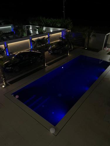 a swimming pool at night with blue illumination at La Mirage Villa in Rrushkull