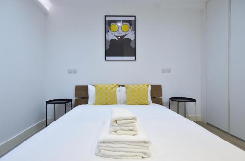 una camera da letto con un letto bianco e asciugamani di Soho 22 Serviced Apartments by Concept Apartments a Londra