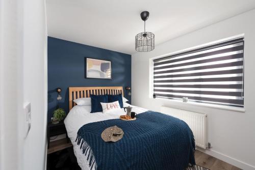 a bedroom with a bed with a blue accent wall at Bay Dream, St Ives in Carbis Bay