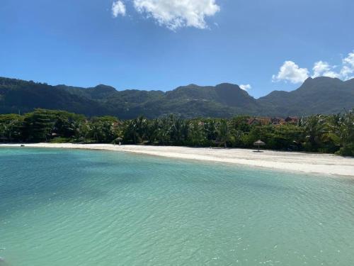 a beach with turquoise water and mountains in the background at Maison La Plage by Simply-Seychelles in Eden Island