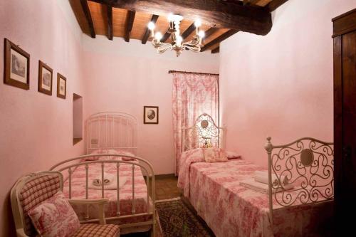 a bedroom with two beds and a chandelier at Le Mascie in Sovicille
