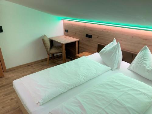 a bedroom with a white bed and a small table at Hotel Garni Siegmundshof - inclusive Joker Card im Sommer in Saalbach Hinterglemm