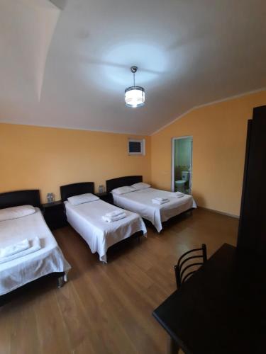 a room with three beds and a table and a room with at Delta Hotel in Ureki