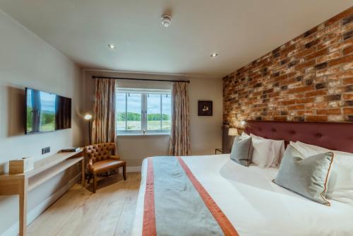 a bedroom with a brick wall and a bed and a desk at Sandburn Hall in York