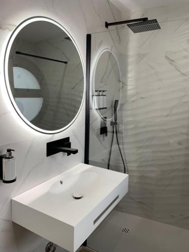 a white bathroom with a sink and a mirror at NerjaRooms in Nerja