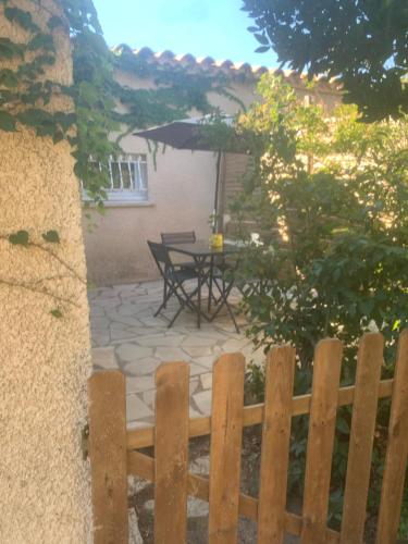 a backyard with a wooden fence and a table at Adorable guest house en pleine nature,la nautique in Narbonne