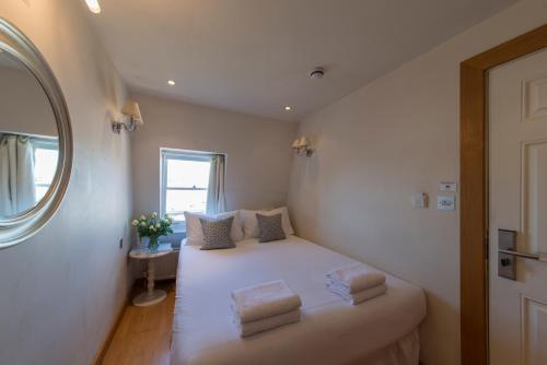 een kleine slaapkamer met een wit bed met 2 kussens bij The Paramount Hotel in Londen