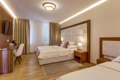 a hotel room with two beds and a desk at Grand Lakes Rooms in Plitvička Jezera