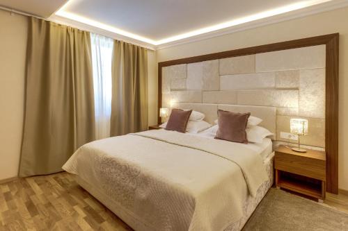 a bedroom with a large white bed and a window at Grand Lakes Rooms in Plitvička Jezera