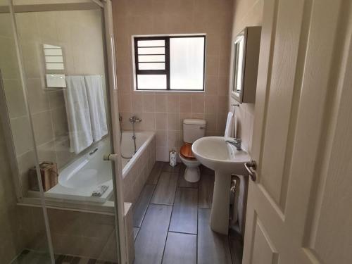 a bathroom with a sink and a tub and a toilet at The Dock in Clarens