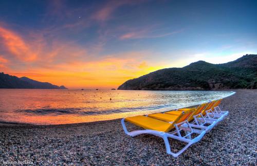 a group of chairs on a beach with a surfboard at Hôtel Le Golfe Ecolabel EU in Porto Ota