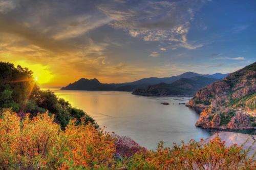 a view of a river at sunset with mountains at Hôtel Le Golfe Ecolabel EU in Porto Ota