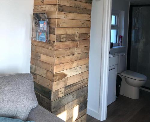 a bathroom with a wall made out of wood at MAESLLAN CABINS - 'Golwg Y Mor' in Cross Inn