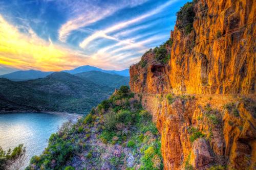 a mountain cliff with a river and a sunset at Hôtel Le Golfe Ecolabel EU in Porto Ota