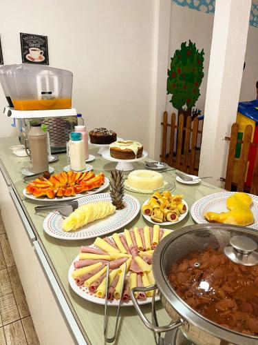 a counter with many plates of food on it at Pousada Loft Praia dos Anjos in Arraial do Cabo