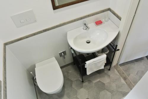 y baño con aseo blanco y lavamanos. en Alloggio ad uso turistico - The Apartment n.1, en Anguillara Sabazia